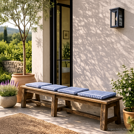 Rustikale Altholz Sitzbank aus Teakholz mit blau karierten Sitzkissen auf sonniger mediterraner Terrasse im Vintage Stil