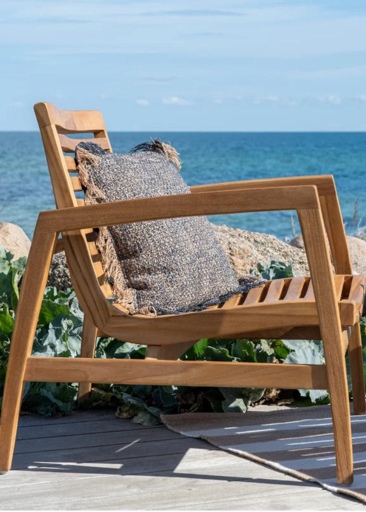 Stilvolle Outdoor Lounge aus Teakholz mit weißen Kissen vor einem modernen Strandhaus