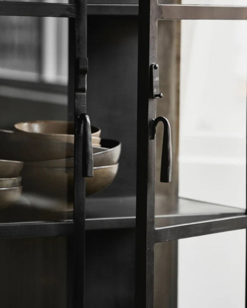 Rustikaler Metallvitrinenschrank im modernen Industrial-Wohnzimmer, dekoriert mit Keramik, Büchern und Pflanzen.