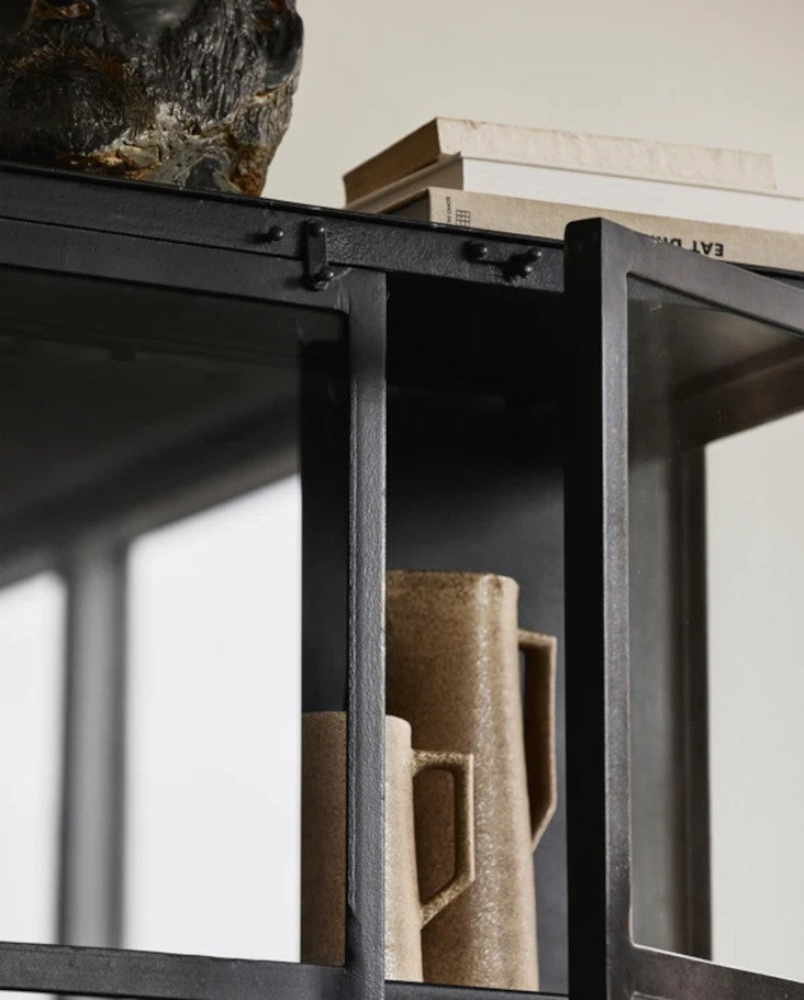 Schwarze Glasvitrine in einer hellen, bunten Landhausküche mit Geschirr, Gläsern und stilvollen Wohnaccessoires.